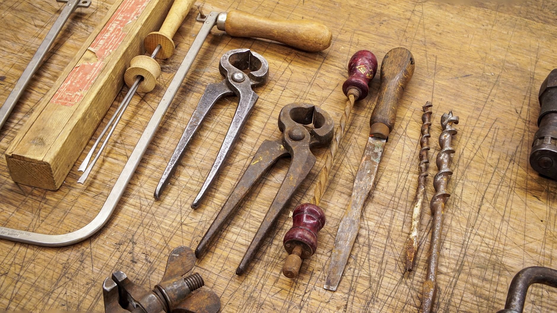 Vintage plumbing and trades tools arranged on a worn wooden workbench
