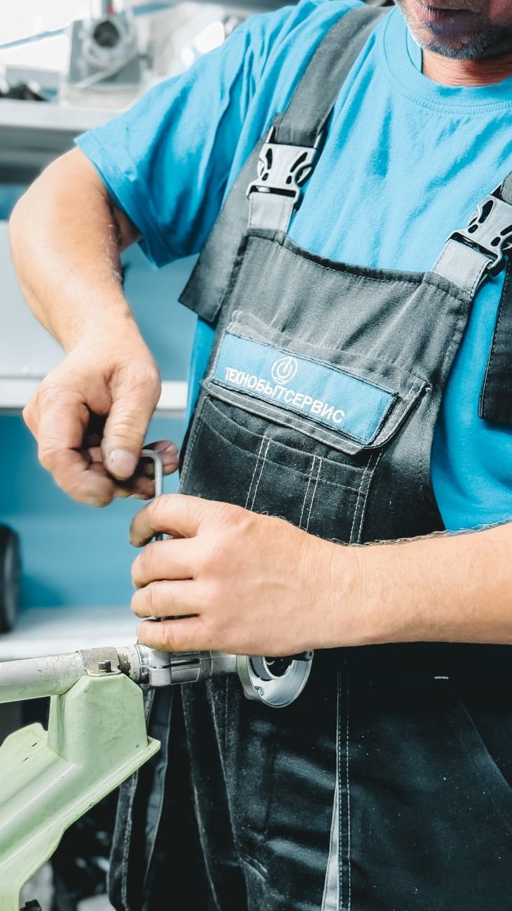Plumber in blue uniform repairing a pipe with a wrench in natural light