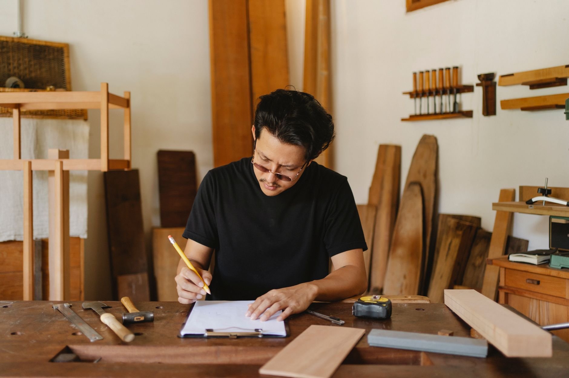 Tradesperson writing notes on a paper clipboard at a workbench